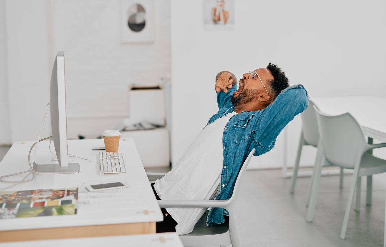 Male employee in blue jacket yawning on the job