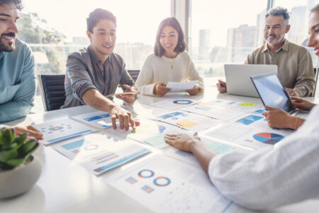 group of employees looking and reading paper reports placed on meeting table