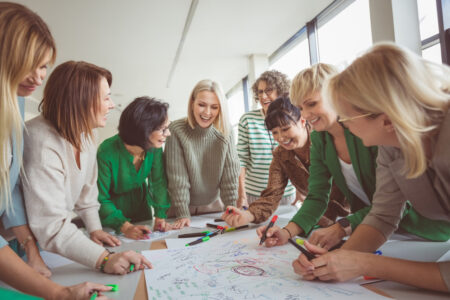 Group of female work colleagues huddled over a meeting table