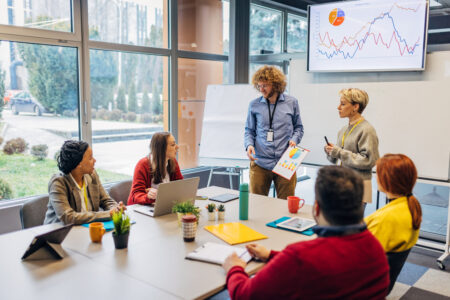 Business meeting in a bright meeting room with data on the screens