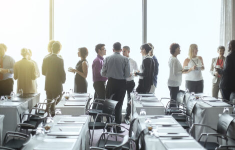 Large group of employees having individual conversations with each other in a large room