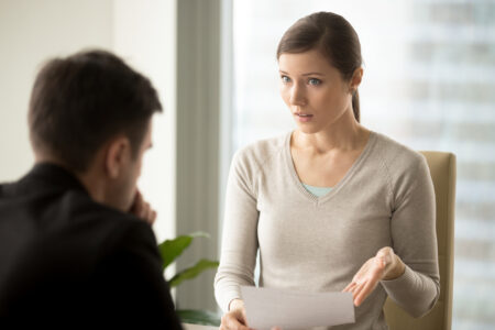 Female boss speaking to male employee with a serious expression