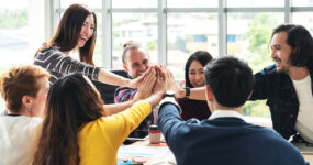 group of young multiethnic diverse people gesture hand high five, laughing and smiling together in brainstorm meeting at office. Casual business with startup teamwork community celebration concept.