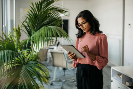 Female employee stood alone using a tablet in a meeting room