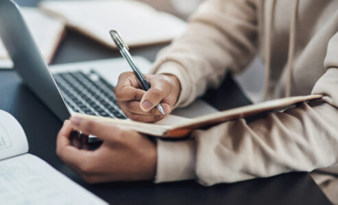 Cropped image of hands writing in a notebook