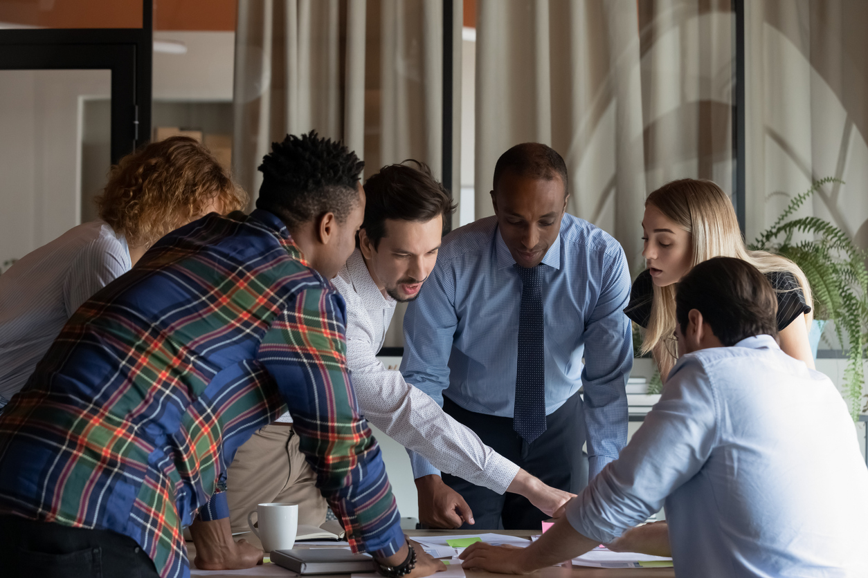 Group of employees plotting a buisness plan whilst leaning over table