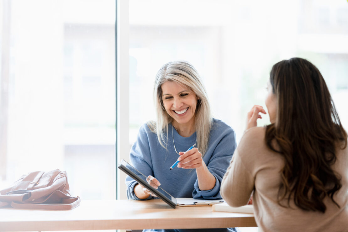 Two females smiling and chatting in casual meeting