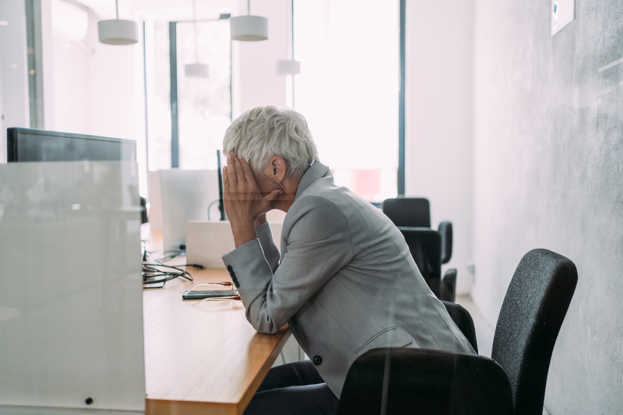 Male sat at desk with hands on his head hiding his face