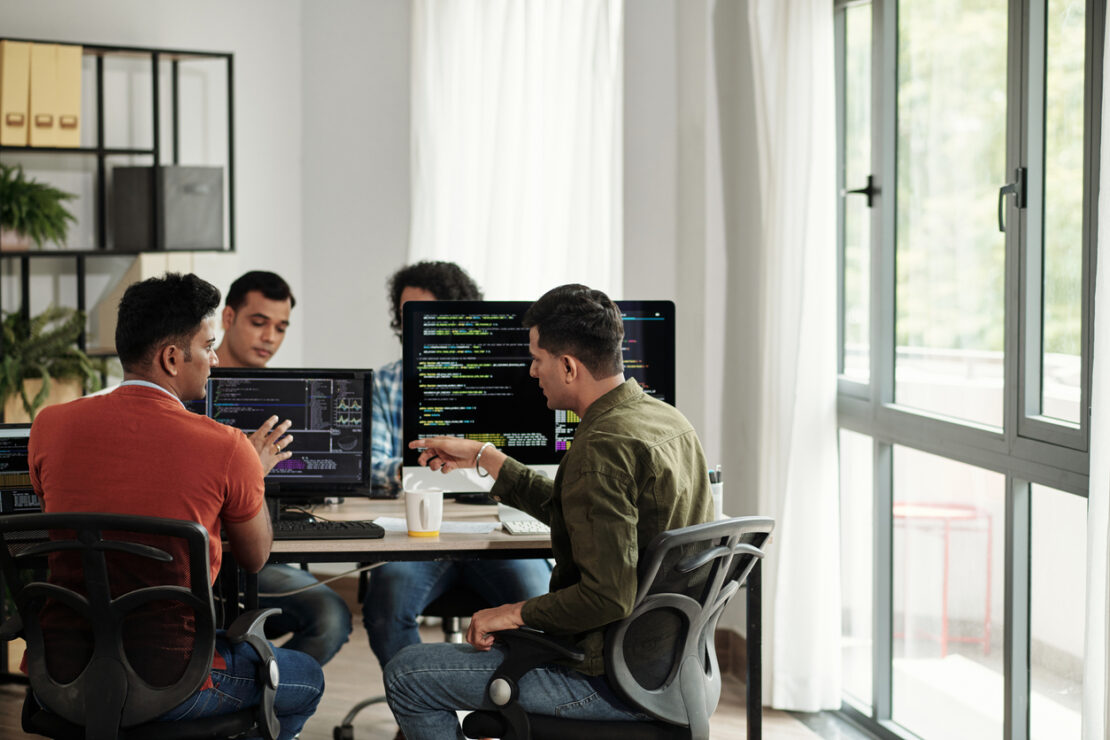 Three software engineers on a office table speaking though work