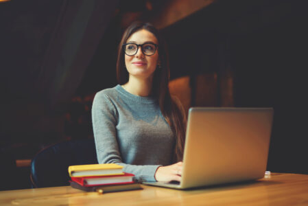 Image of a female alone smiling to herself whilst on her computer