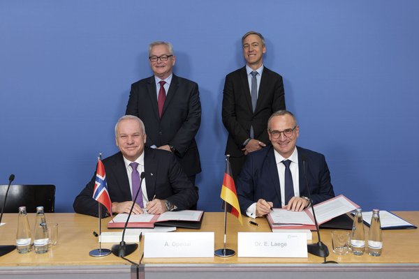 Four businessmen in suits signing sales agreement