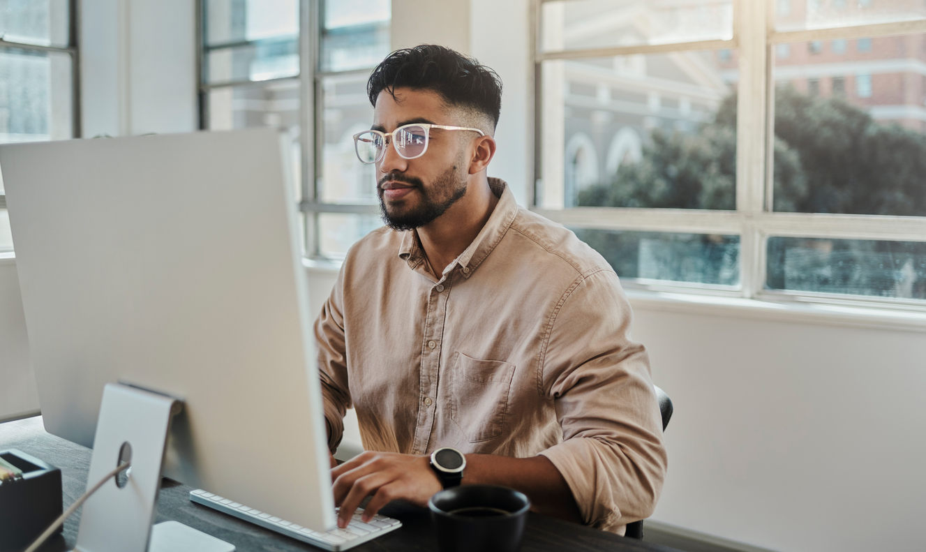 Man in light brown top working on a computer monitor concentrating