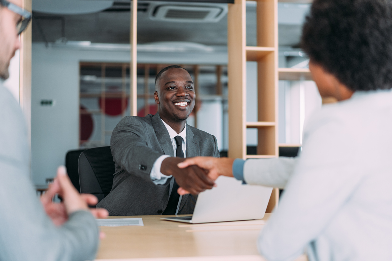 Dark skinned man shaking hands with employer after successful interview