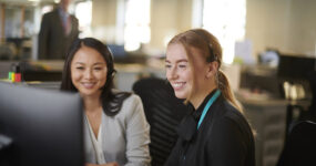 Two females laughing and smiling together whilst collaborating