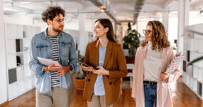 Three employees walking through an open office space